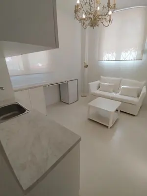a white living room with a couch and a chandelier at AMG Stylish Small Apartment in Pagkrati Close to Metro in Athens