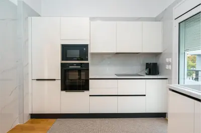 a white kitchen with white cabinets and a microwave at YourHostess in Athens