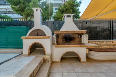 a outdoor pizza oven in a patio with a fence at YourHostess in Athens
