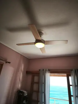 a ceiling fan in a room with a window at Vintage house by the sea in althea in Aghia Marina