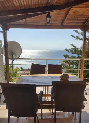 a table and chairs on a patio with a view of the ocean at Vintage house by the sea in althea in Aghia Marina