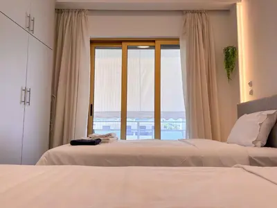 a bedroom with two beds and a large window at Cozy Flat near Glyfada Center in Athens