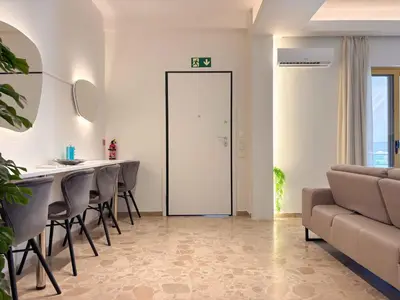 a living room with a table and chairs and a door at Cozy Flat near Glyfada Center in Athens