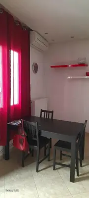 a dining room with a table and chairs and red curtains at Dimis Apartment in Athens