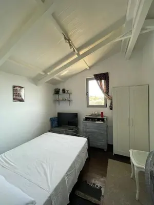 a bedroom with a white bed and a desk at Simple Stay Vari's House in Vari