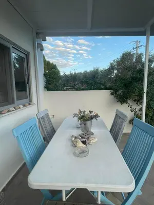a table with chairs and a vase of flowers on a patio at Simple Stay Vari's House in Vari