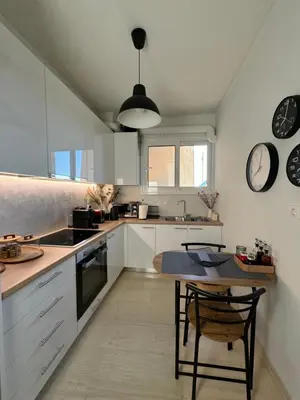 a kitchen with white cabinets and a table and a clock at The rock view apartment in Athens