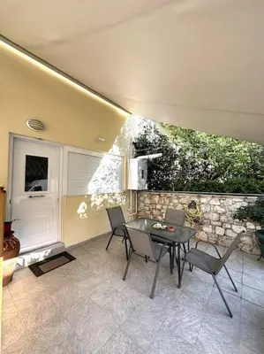 a patio with a table and chairs and a stone wall at Tide and Tonic spacious 1bd apartment with extra Loft Style Sleeping Area, Paleo Faliro in Athens