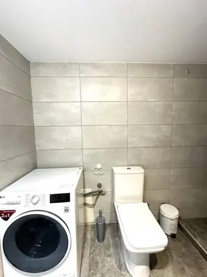 a bathroom with a washing machine and a toilet at Tide and Tonic spacious 1bd apartment with extra Loft Style Sleeping Area, Paleo Faliro in Athens