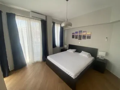 a bedroom with a white bed and a large window at Ydrea Piraeus port apartment in Piraeus