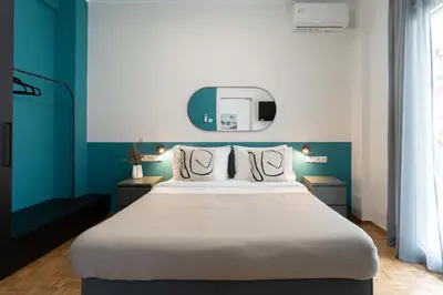 a bedroom with a large bed with blue walls at Phaedrus Living Zografou Azure Aura in Athens