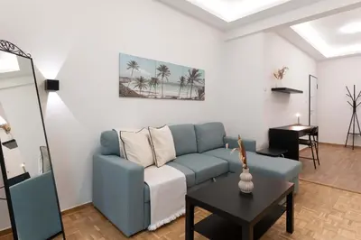 a living room with a blue couch and a table at Phaedrus Living Zografou Azure Aura in Athens