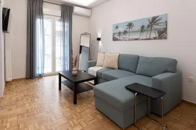 a living room with a blue couch and a table at Phaedrus Living Zografou Azure Aura in Athens