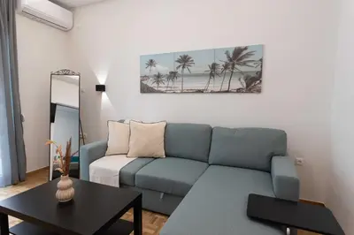 a living room with a blue couch and a table at Phaedrus Living Zografou Azure Aura in Athens