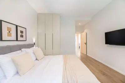 a white bedroom with a large bed and a flat screen tv at Lovely 3BR Apartment in Pangrati by UPSTREET in Athens