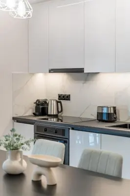 a kitchen with white cabinets and a table with a stool at Lovely 3BR Apartment in Pangrati by UPSTREET in Athens