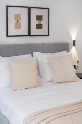 a bed with white pillows and two pictures on the wall at Lovely 3BR Apartment in Pangrati by UPSTREET in Athens