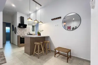 a kitchen with white walls and a mirror and stools at NEW! Incredible 1BR Apt in Koukaki with AC in Athens