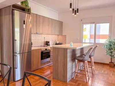 a kitchen with a refrigerator and a counter with chairs at Light & Spacious Apartment near Glyfada Center in Athens