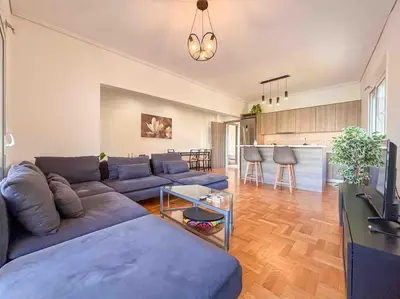 a living room with a blue couch and a kitchen at Light & Spacious Apartment near Glyfada Center in Athens