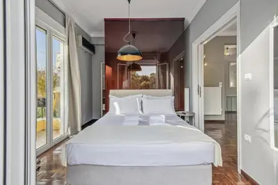 a large white bed in a room with windows at the Acropolis Noir Penthouse in Athens