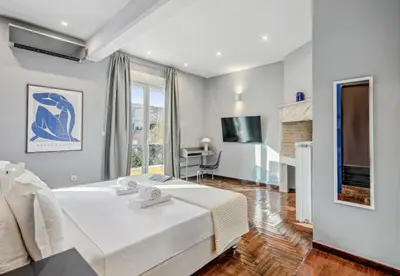 a bedroom with a large white bed and a desk at the Acropolis Noir Penthouse in Athens
