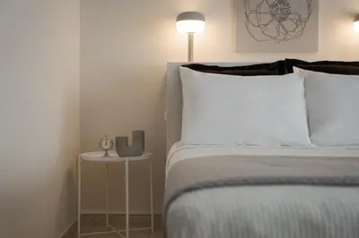 a bedroom with a bed and a table with a lamp at Athenian Comfort Apartments in Athens