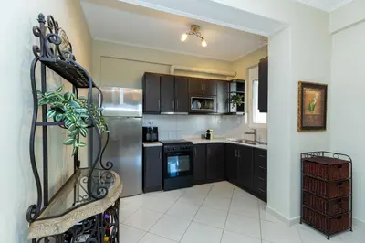 a kitchen with black cabinets and a stainless steel refrigerator at Helios Residence by A&D Properties in Porto Rafti