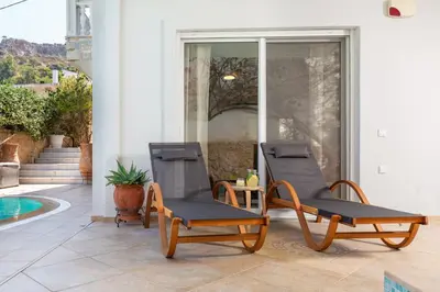 two chairs on a patio with a pool at Helios Residence by A&D Properties in Porto Rafti