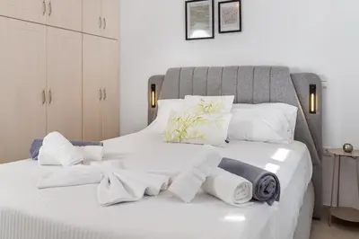 a bedroom with a white bed with towels on it at Helios Residence by A&D Properties in Porto Rafti