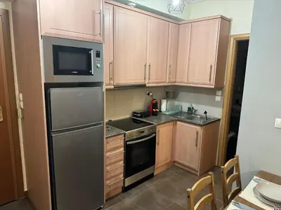 a kitchen with wooden cabinets and a stainless steel refrigerator at Athens view penthouse with private parking in Athens