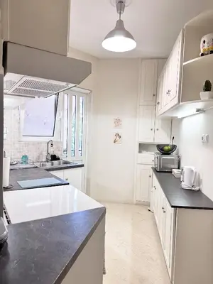 a kitchen with white cabinets and a black counter top at Sea the City - Chic 2-BDR Escape with Spacious Living in Athens