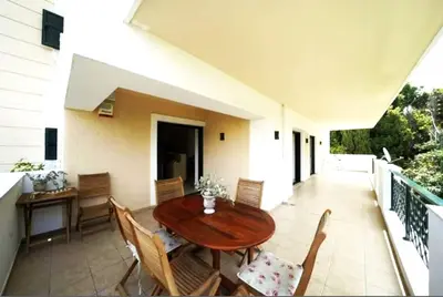 a wooden table and chairs on a balcony at Voula Family Home in Athens