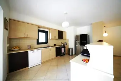a large kitchen with wooden cabinets and white appliances at Voula Family Home in Athens