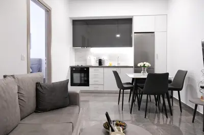 a living room with a couch and a table with chairs at Cozy Home With Cooking Near Tram in Piraeus