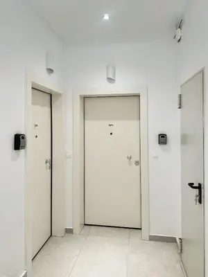 a corridor with three doors in a white room at Cozy Home With Cooking Near Tram in Piraeus