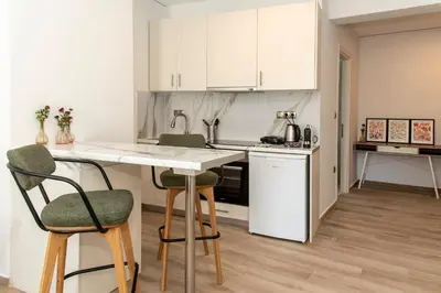 a kitchen with white cabinets and a table and chairs at Αthens Black & White Escape in Athens