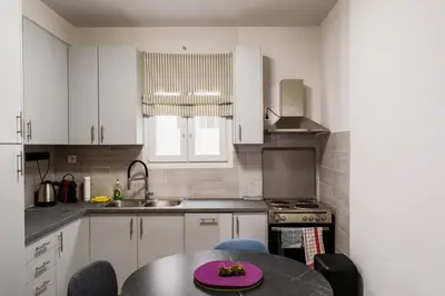 a kitchen with white cabinets and a table with a pink plate on it at Stylish and cozy flat at pagrati in Athens