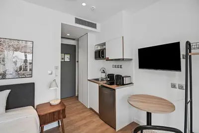 a room with a bed and a kitchen with a table at Limehome Piraeus Olive in Piraeus