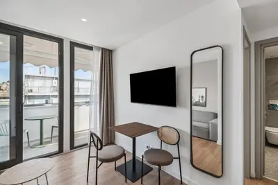 a living room with a table and chairs and a tv at Limehome Piraeus Olive in Piraeus
