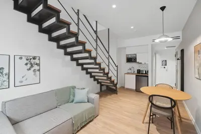 a living room with a couch and a staircase at Limehome Piraeus Olive in Piraeus