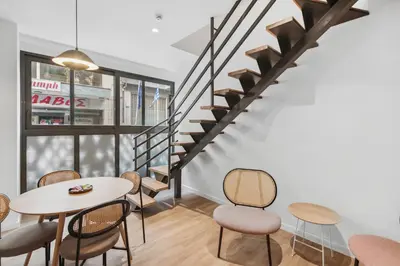 a room with a table and chairs and a staircase at Limehome Piraeus Olive in Piraeus