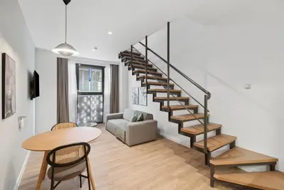 a living room with a spiral staircase and a table at Limehome Piraeus Olive in Piraeus