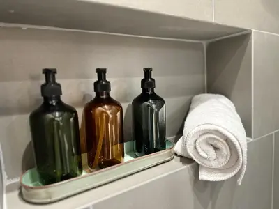 three bottles in a shelf in a bathroom with a towel at Estia Athens Apartment in Athens