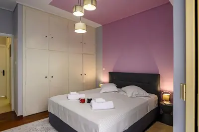 a bedroom with purple walls and a bed with towels at Luxury 2 bed Urban Oasis in the Heart of Athens in Athens
