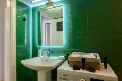 a green bathroom with a sink and a mirror at Luxury 2 bed Urban Oasis in the Heart of Athens in Athens