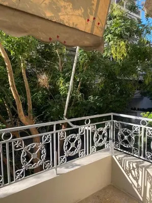 a balcony with a white railing and some trees at Veli's Apartment in Athens