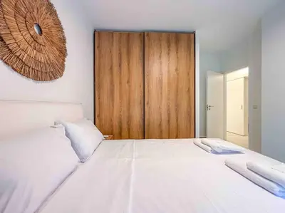 a bedroom with a large white bed with a wooden cabinet at Elegant Flat in Glyfada Center in Athens