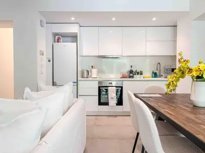 a kitchen with a wooden table and white cabinets at Elegant Flat in Glyfada Center in Athens