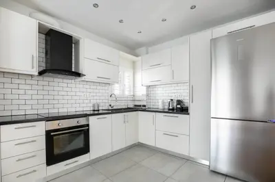 a kitchen with white cabinets and a stainless steel refrigerator at Dew 1-Bedroom Apartment in Athens in Athens
